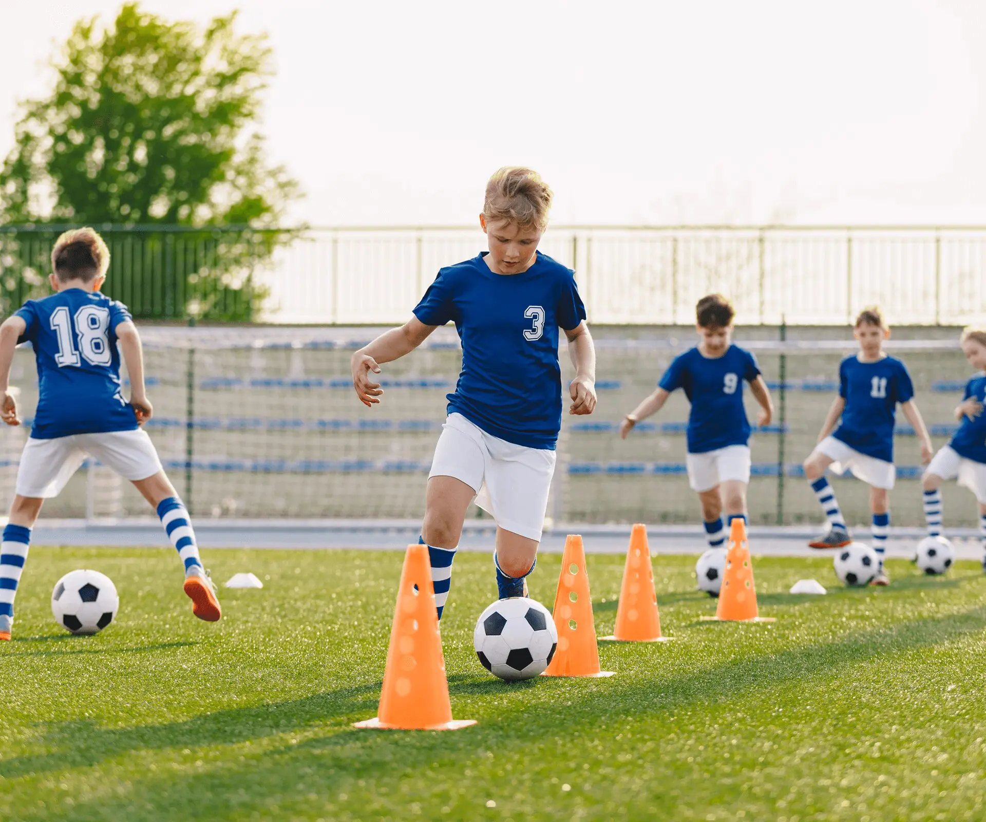 Boys practicing soccer drills with cones.