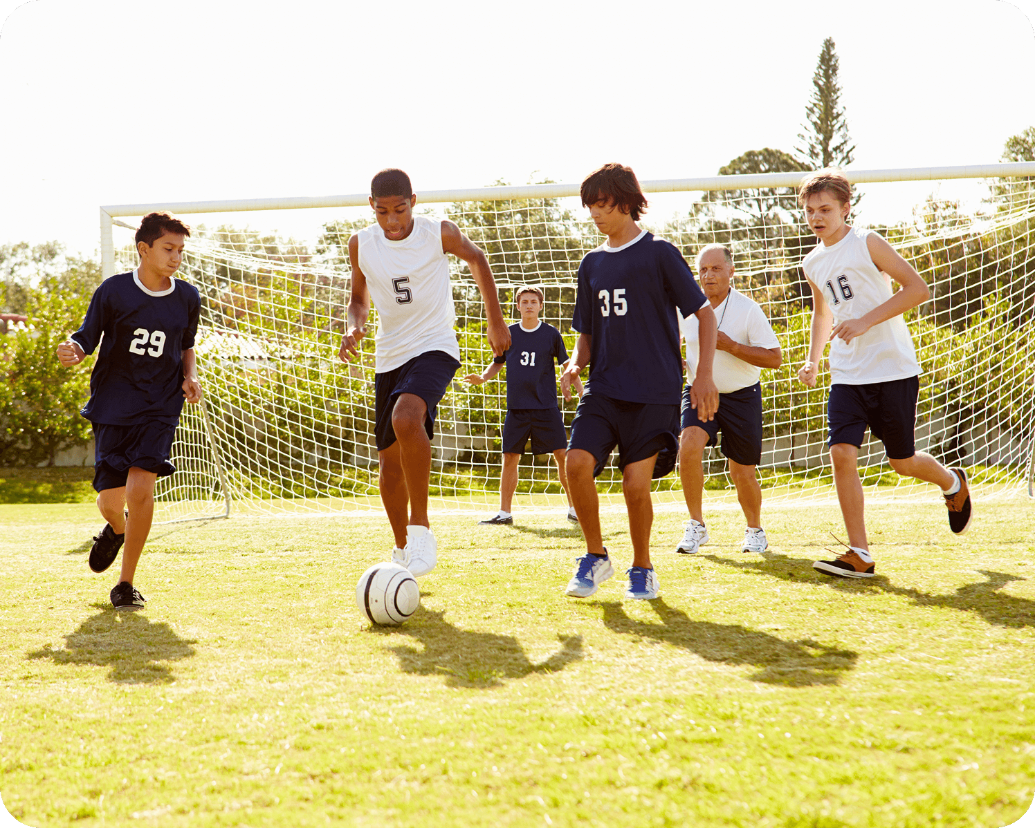 Boys playing soccer on a sunny field.